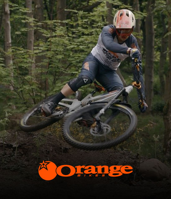 Image of a man riding an Orange Bike along a trail