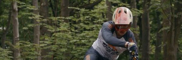 Image of a man riding an Orange Bike along a trail