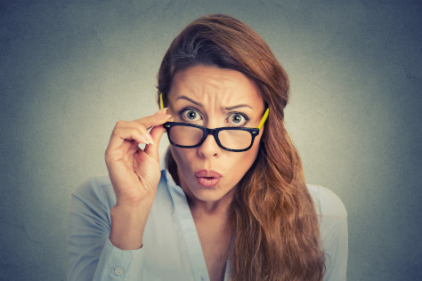 Surprised woman looks over her glasses